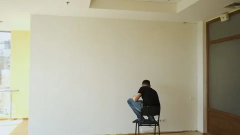 Young brunette master makes repairs in a large spacious office with panoramic Stockbeeldmateriaal 132792603