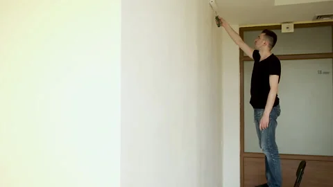 Young brunette master makes repairs in a large spacious office with panoramic Vídeo Stock 132792634