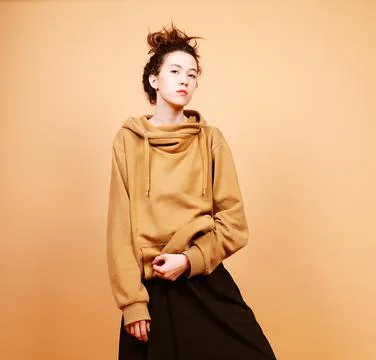 Young brunette model posing in studio, beige background Stock Photos