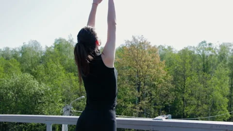 Young brunette performs breathing exercises on the railway bridge over the 스톡 동영상 89852774