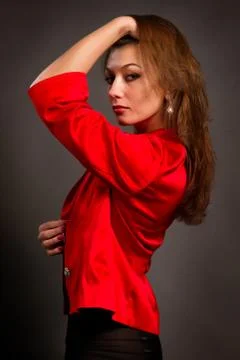 Young brunette in a red jacket on a gray background Stock Photos