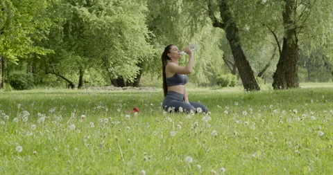 The young brunette trainer, after a complex of exercises, sitting on the grass Stock Footage 217918071
