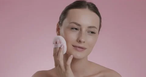 Young brunette using soft sponge for applying powder on face Stock Footage 158755701