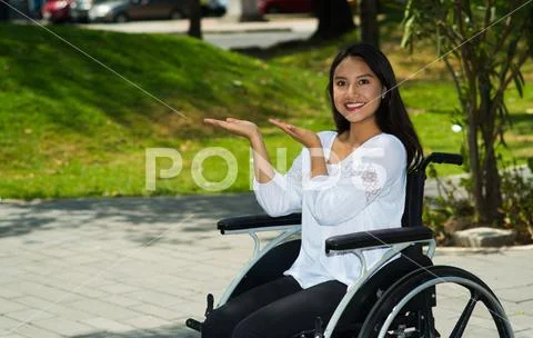 Young brunette woman sitting in wheelchair smiling with positive attitude Stock Photos