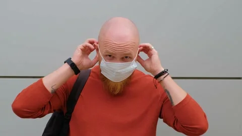 Young brutal guy with a red beard puts on a medical mask on his face.Protection Stock Footage 139111534