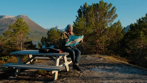 Young brutal man looking a map in a forest at sunset. Norway forest. Wooden Stock Footage 109369636