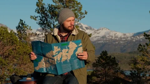 Young brutal man looking a map in a forest at sunset. Norway forest. Wooden Stock Footage 109369808
