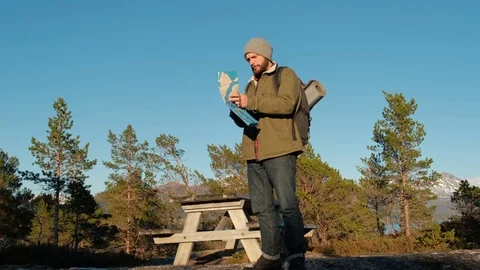 Young brutal man looking a map in a forest at sunset. Norway forest. Wooden Stock Footage 109370065