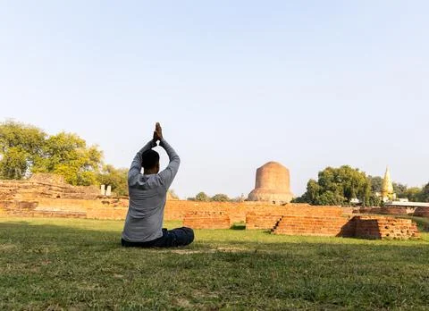 Young Buddhist devotee performing holy mediation at sarnath dhamek stupa ru.. Stock Photos