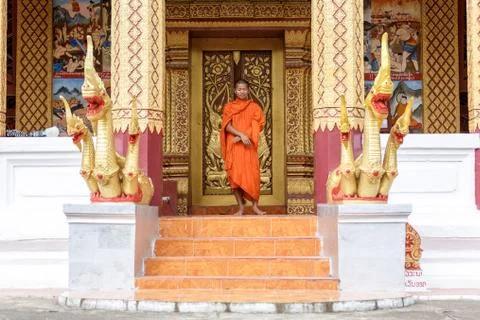 Young buddhist monk standing in front of monastery Stock Photos