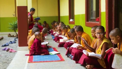 Young Buddhist monks sitting and murmuring at the monastery Stock Footage 77443891