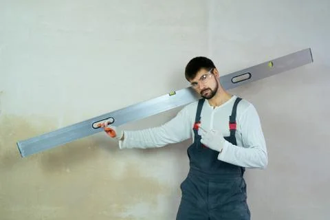 Young builder with construction ruler shows forefinger in interior free space Stock Photos