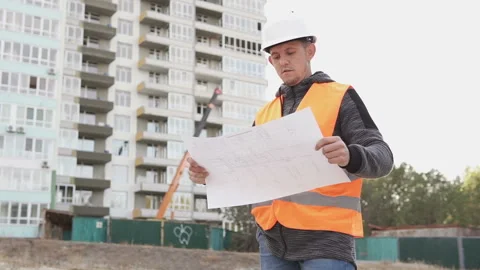 Young builder at a construction site walks with drawings Stock Footage 118134439