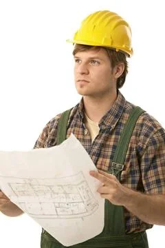 Young builder holding floor plan Young builder wearing hardhat, holding fl... Stock Photos
