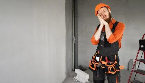 Young builder sleeping tired with closed eyes showing night gesture at cons.. Stock Photos