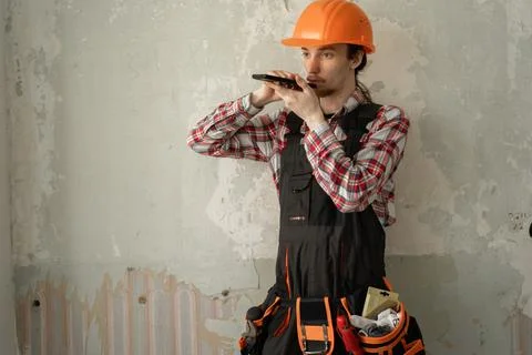 Young builder with smartphone at site for communication or construction mak.. Stock Photos