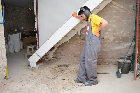 Young builder thinking how to solve a problem at the construction site. Stockfoto's