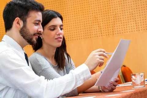 Young business couple reviewing documents in conference hall. Stock Photos