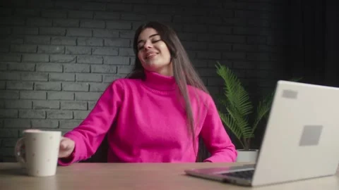 A young business lady finishes typing and sips her coffee. A brunette girl in Video stock 233062653