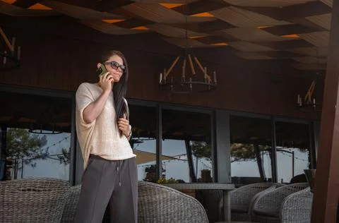 Young business lady is talking using her smartphone while standing in a cafe 库存照片