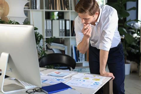 Young business man analyzing data using computer while working in the office. Stock Photos