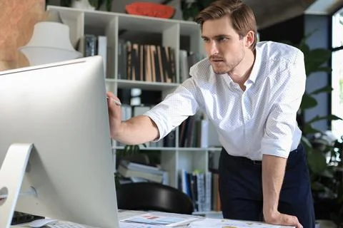 Young business man analyzing data using computer while working in the office. Stock Photos