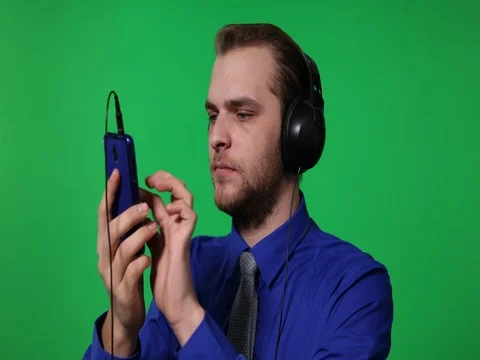 Young Business Man Browsing Mobile Phone with Headphones Green Screen Background Stock Footage 77007454