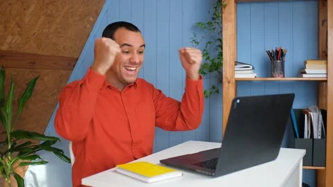 Young business man gets successful news, sits at table with laptop in home Video stock 148228317