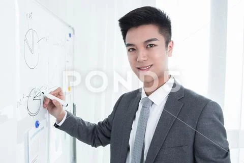 Young business man or teacher showing on white board Stock Photos