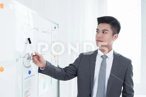 Young business man or teacher showing on white board Stock Photos