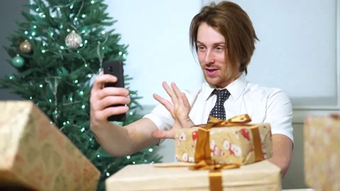 Young business man talking to camera sitting at office.shows new year gifts Vidéo 164042137