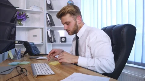 Young business man working on computer and making notes in notebook while Video stock 77135372