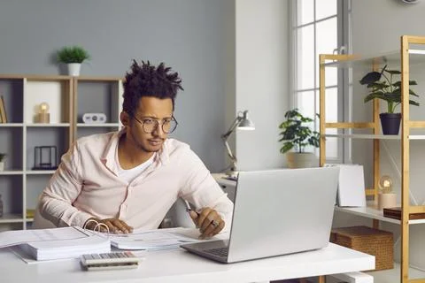 Young business man working on a laptop at office and looking on a computer Stock Photos