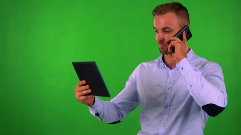 Young business man works on tablet and phone with smartphone - green screen Stock Footage