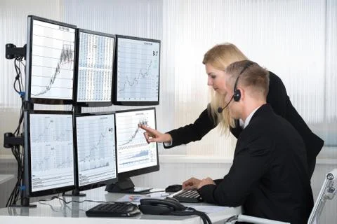 Young business people analyzing data displayed on computer screens in office Foto stock