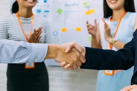 Young business people shaking hands and cheering crowd clapping background Stock Photos
