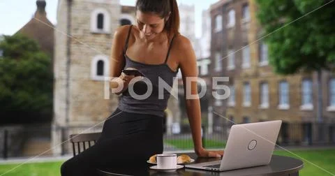 Young business woman with coffee multitasking texting and working on laptop Stock Photos