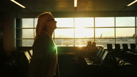 Young business woman going along the airport terminal. At sunset. Steadicam shot Stock Footage