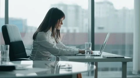 Young business woman working at a laptop in modern office. she smiling and take Stock Footage