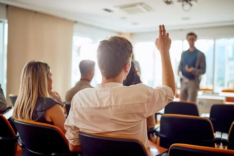A young businessman asks a question during a business lecture in the confer.. Stock Photos
