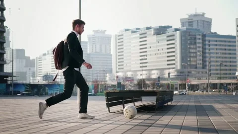 A young businessman with a brown backpack pushes the ball against the background Stock Footage 165385257