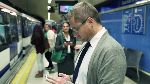 Young businessman with cellphone waiting on platform and getting on metro  HD Stock Footage