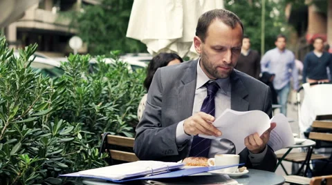 Young businessman comparing, checking documents sitting in cafe HD Stock Footage 43332199