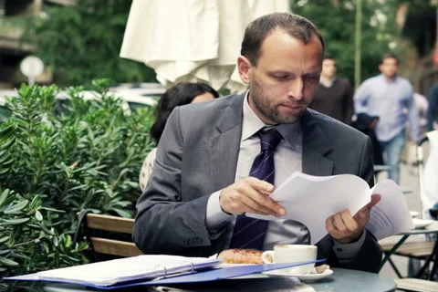 Young businessman comparing, checking documents sitting in cafe NTSC Stock Footage 43332263