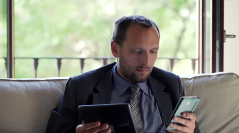 Young businessman comparing data on tablet computer and smartphone at home HD Stock Footage 46216418