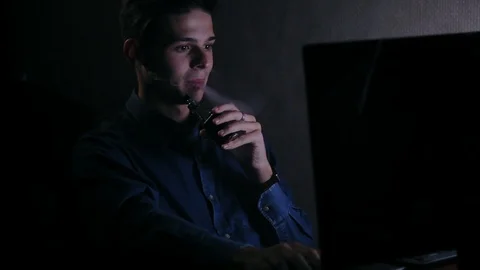 Young businessman doing tasks and vaping in the office at night Stock Footage 99932093