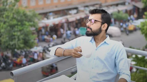 A young businessman drinking coffee while traffic is moving in the background. Stock Footage 94131532