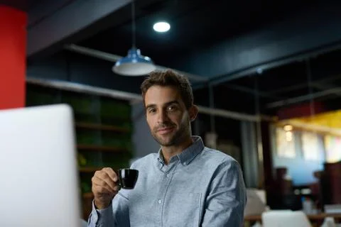 Young businessman drinking coffee while working at his desk Foto stock