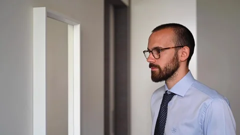 Young businessman getting ready facing mirror and adjusting his protection mask Stock Footage 128931645