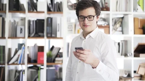 Young businessman in glasses web browsing with his smartphone, pan shot 스톡 동영상 80433720